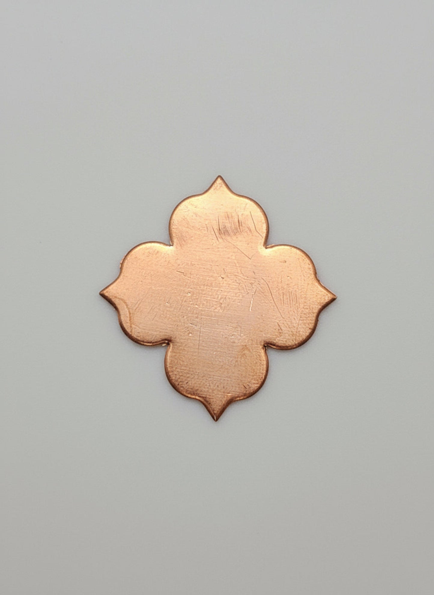 Copper leaf-shaped object on a black surface with measurement markings