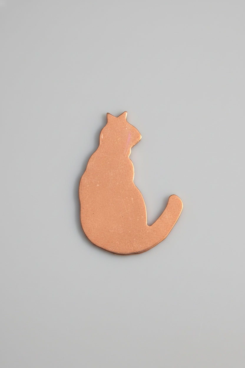 Copper cat-shaped object on a black surface with measurement markings