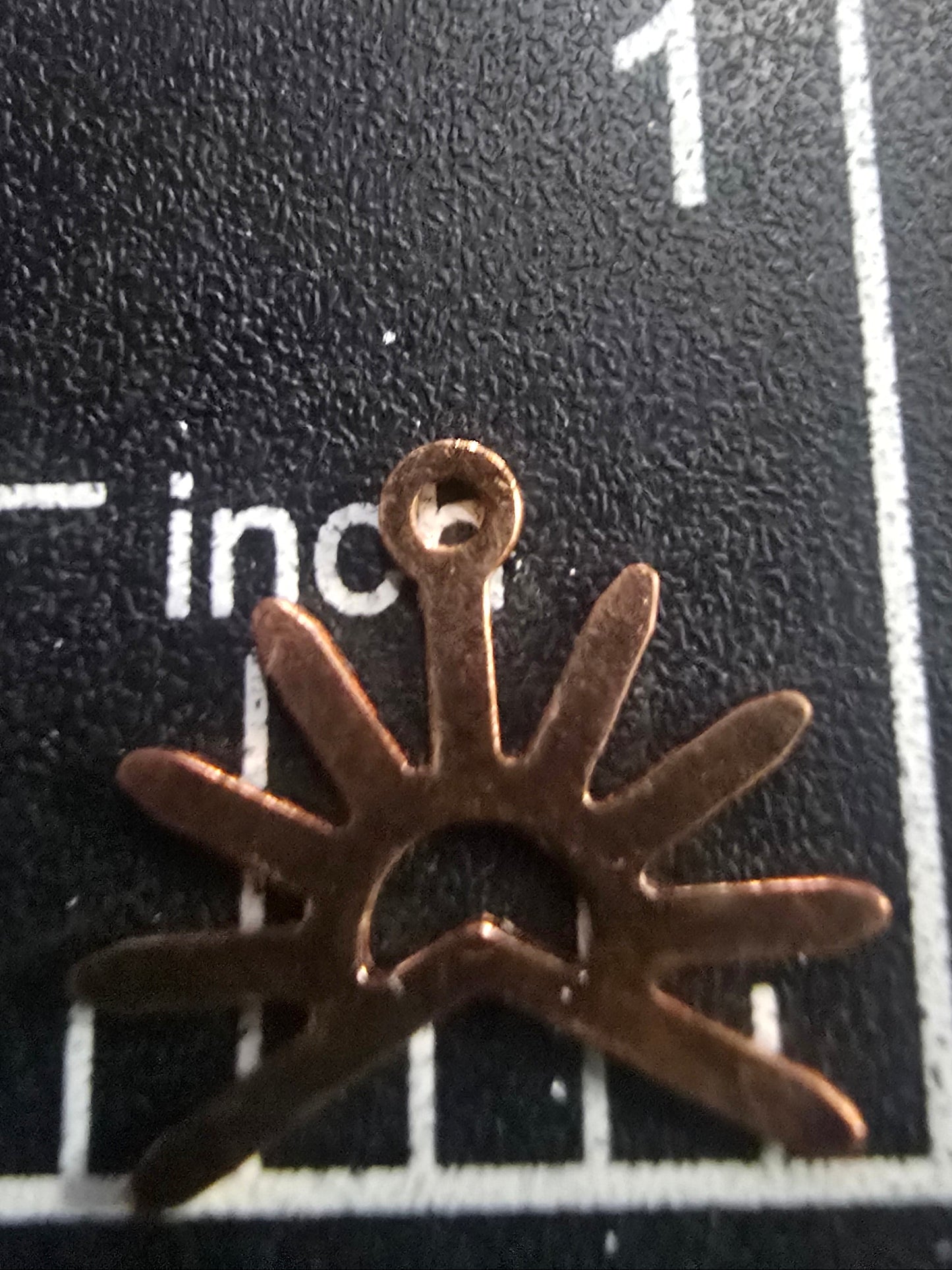 Bronze star-shaped object on a black surface with measurement markings