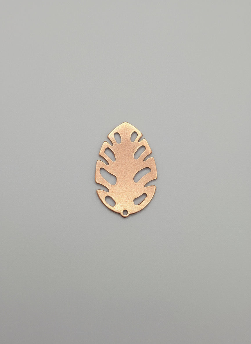 Copper leaf-shaped object on a black surface with measurement markings