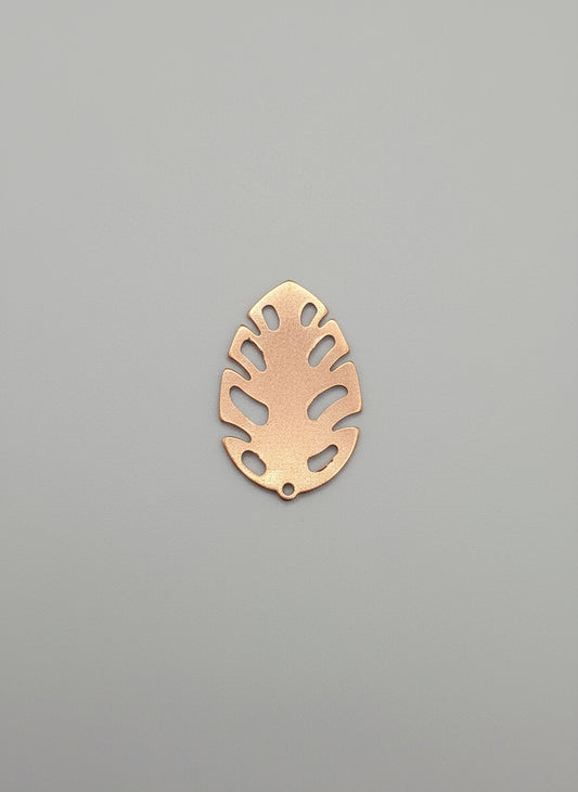 Copper leaf-shaped object on a black surface with measurement markings