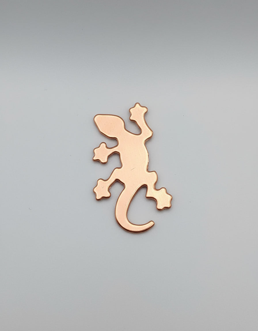 Copper lizard-shaped object on a black surface with measurement markings