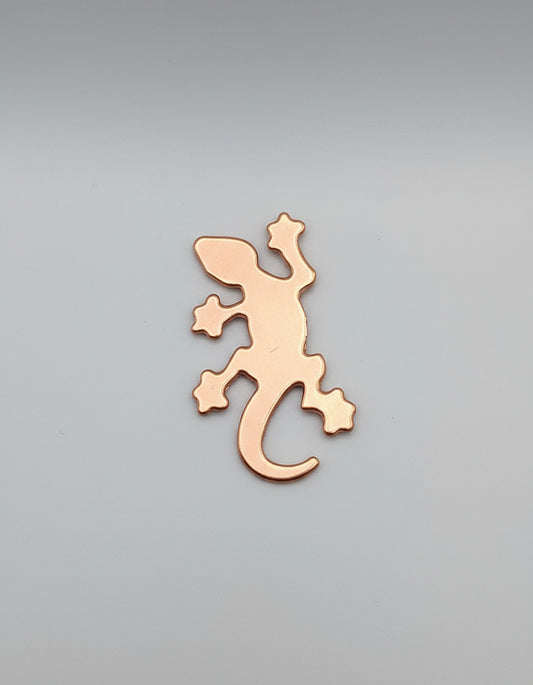 Copper lizard-shaped object on a black surface with measurement markings