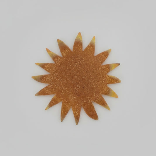 Metallic sun-shaped object on a black surface with measurement markings