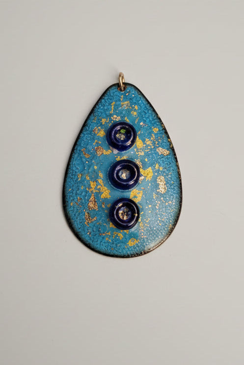 Blue oval object with three dark circles on a cutting mat with measurements