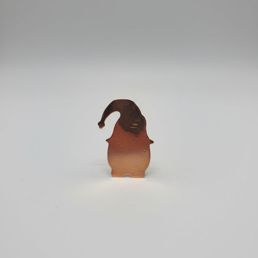 Small Copper-colored metal object on a black surface with measurement markings