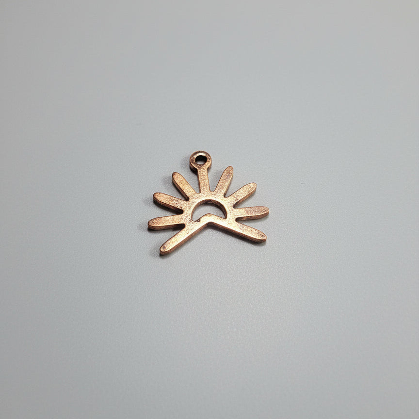 Copper sun-shaped object on a black surface with measurement markings