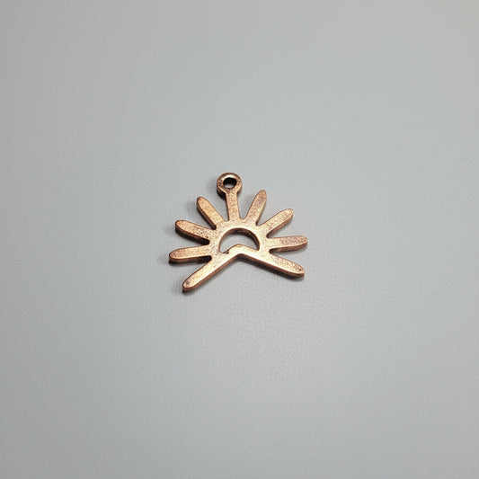 Copper sun-shaped object on a black surface with measurement markings