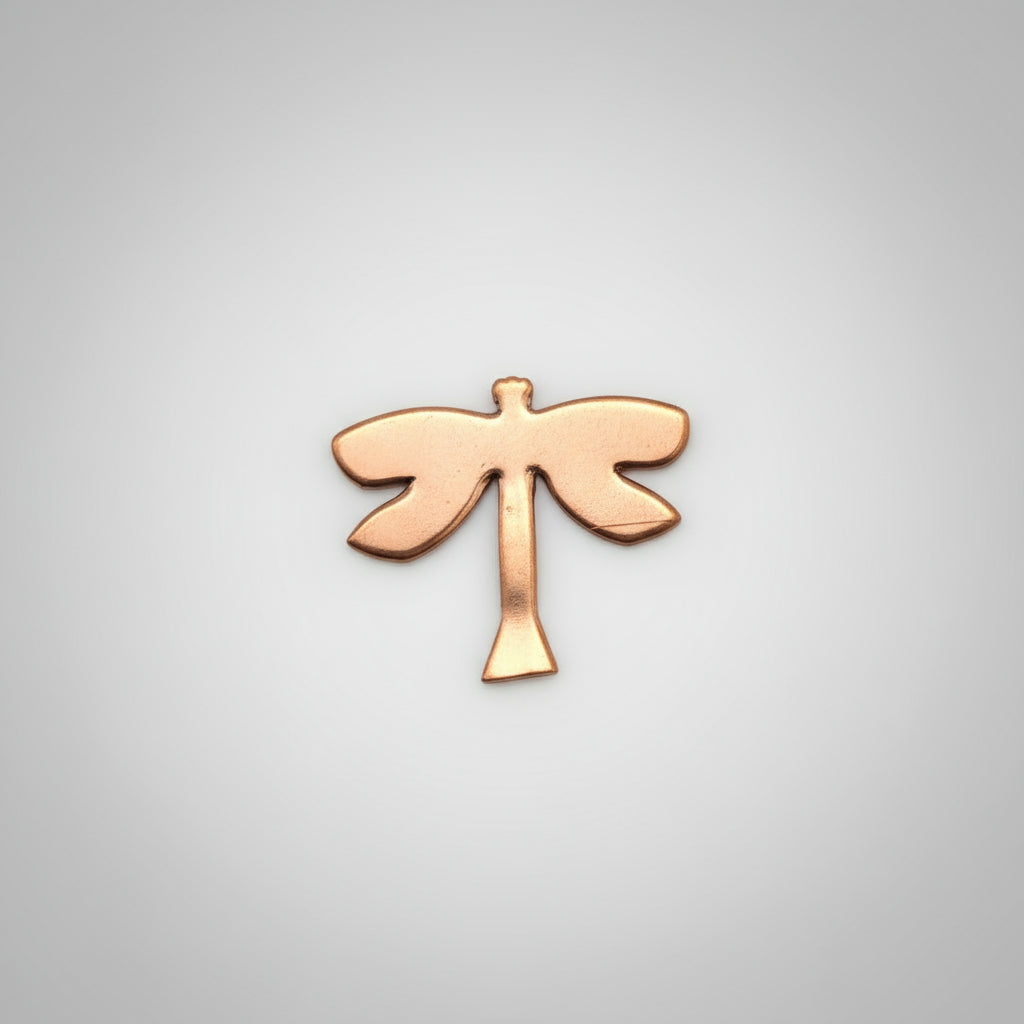 Copper dragonfly-shaped object on a black cutting mat with measurements.