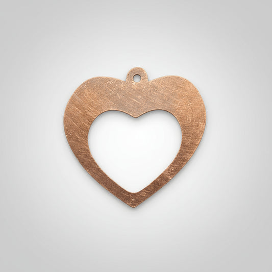 Copper heart-shaped pendant on a black background with measurement scale