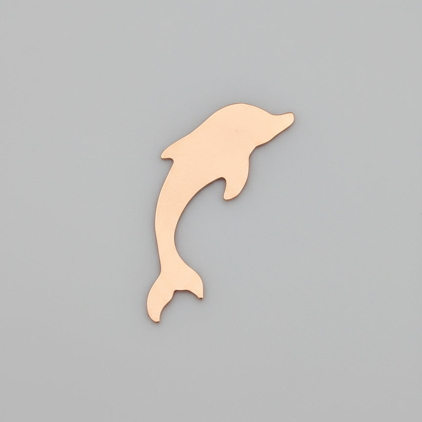 Copper  dolphin-shaped object on a ruler for scale