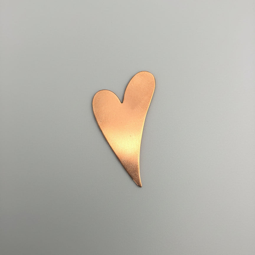 Copper heart-shaped object on a black surface with measurement grid