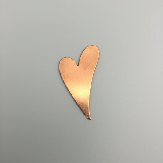Copper heart-shaped object on a black surface with measurement grid