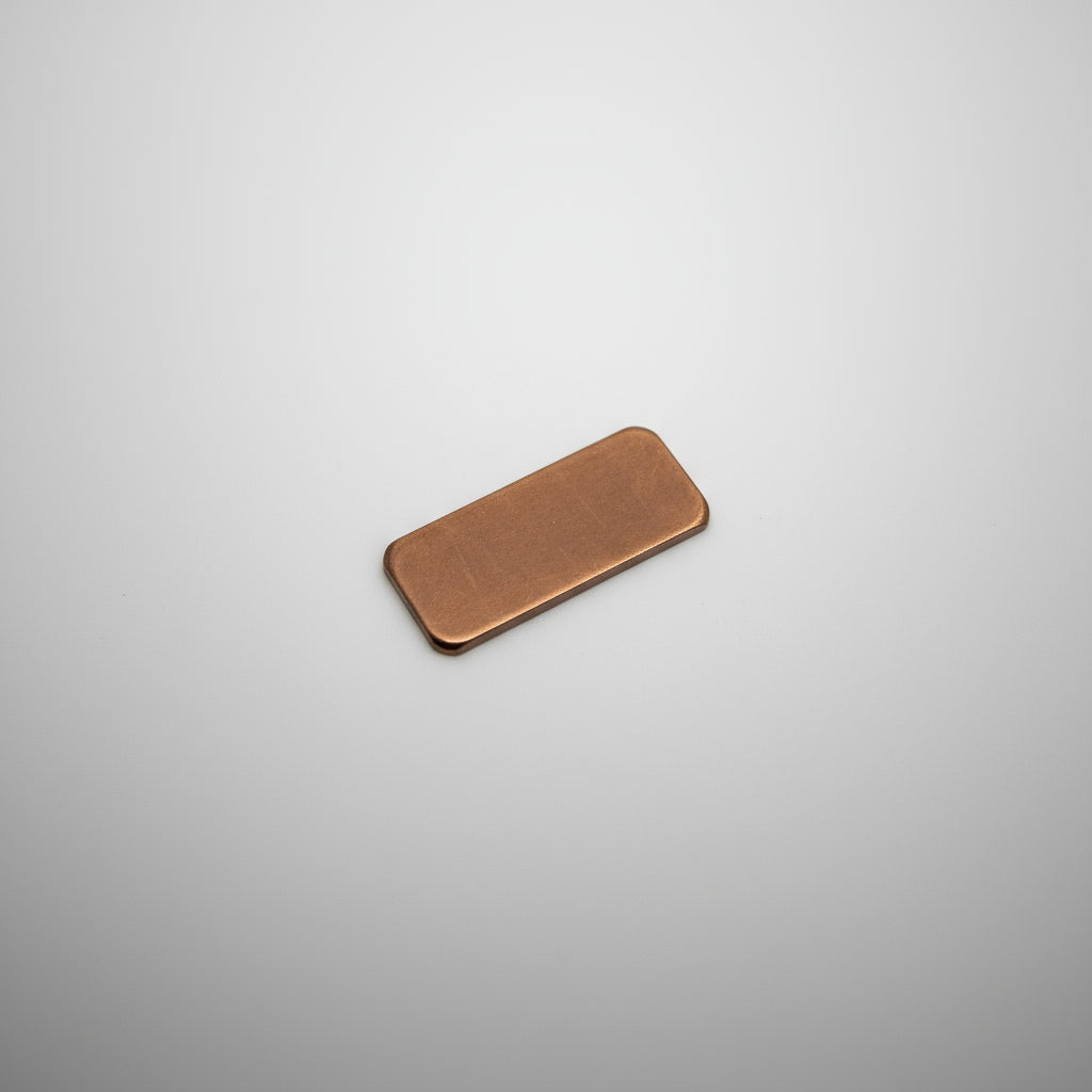 Small rectangular metal object on a black surface with measurement grid