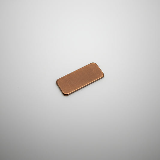 Small rectangular metal object on a black surface with measurement grid