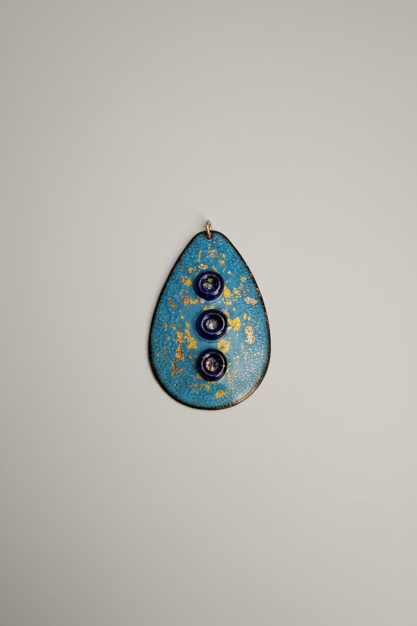 Blue oval object with three dark circles on a cutting mat with measurements